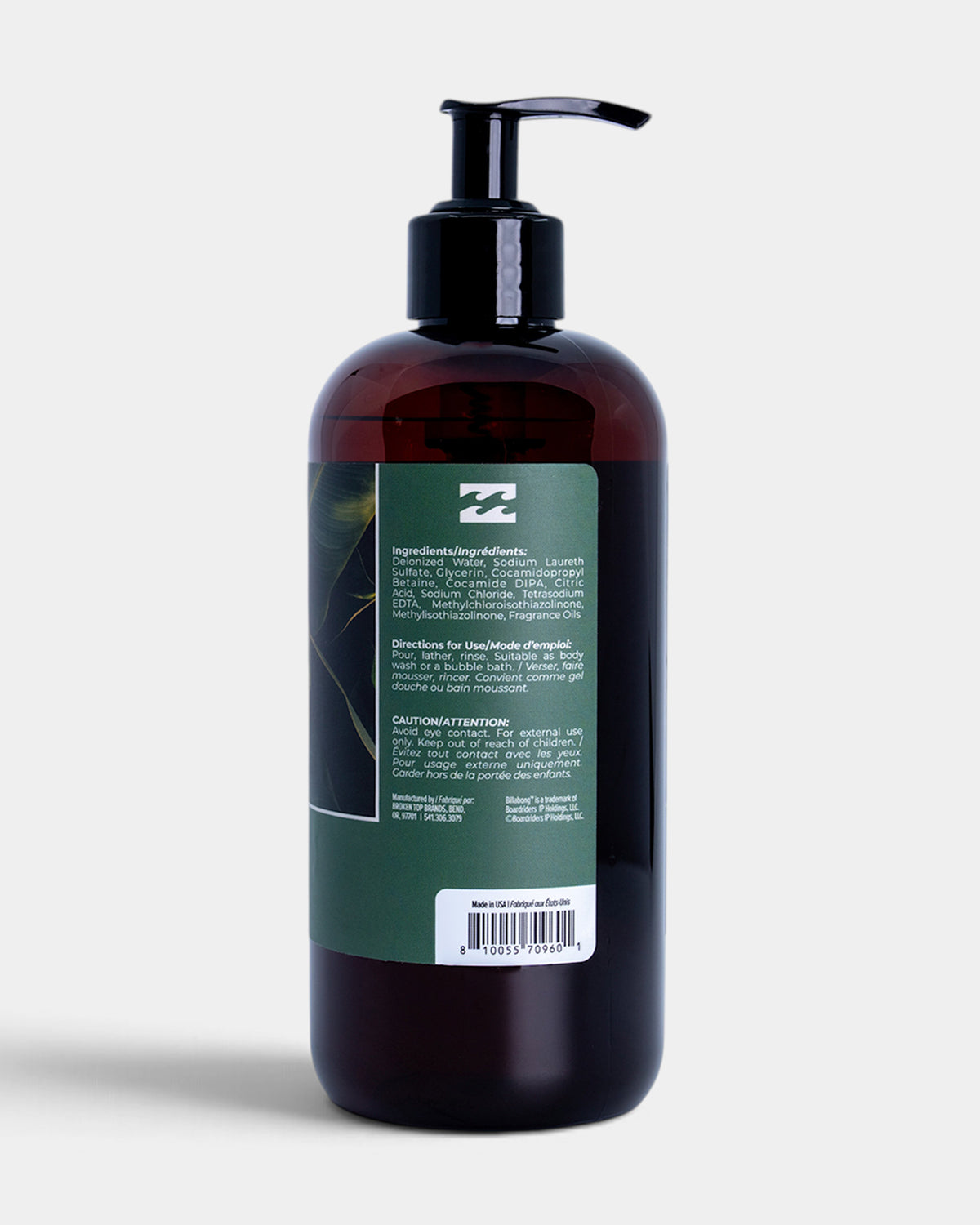 A dark amber plastic pump bottle of hair product with a black dispenser and a green label, shown from the back against a light gray background.