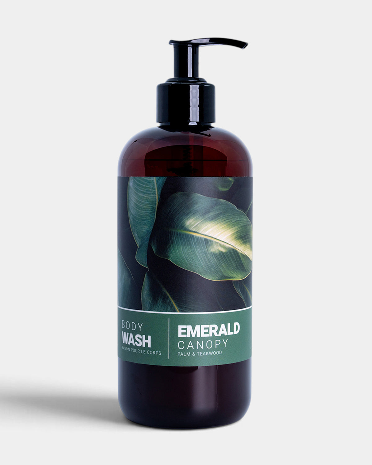 Emerald Canary body wash in a dark amber bottle with a black pump dispenser and a green tropical leaf label, set against a light gray background.