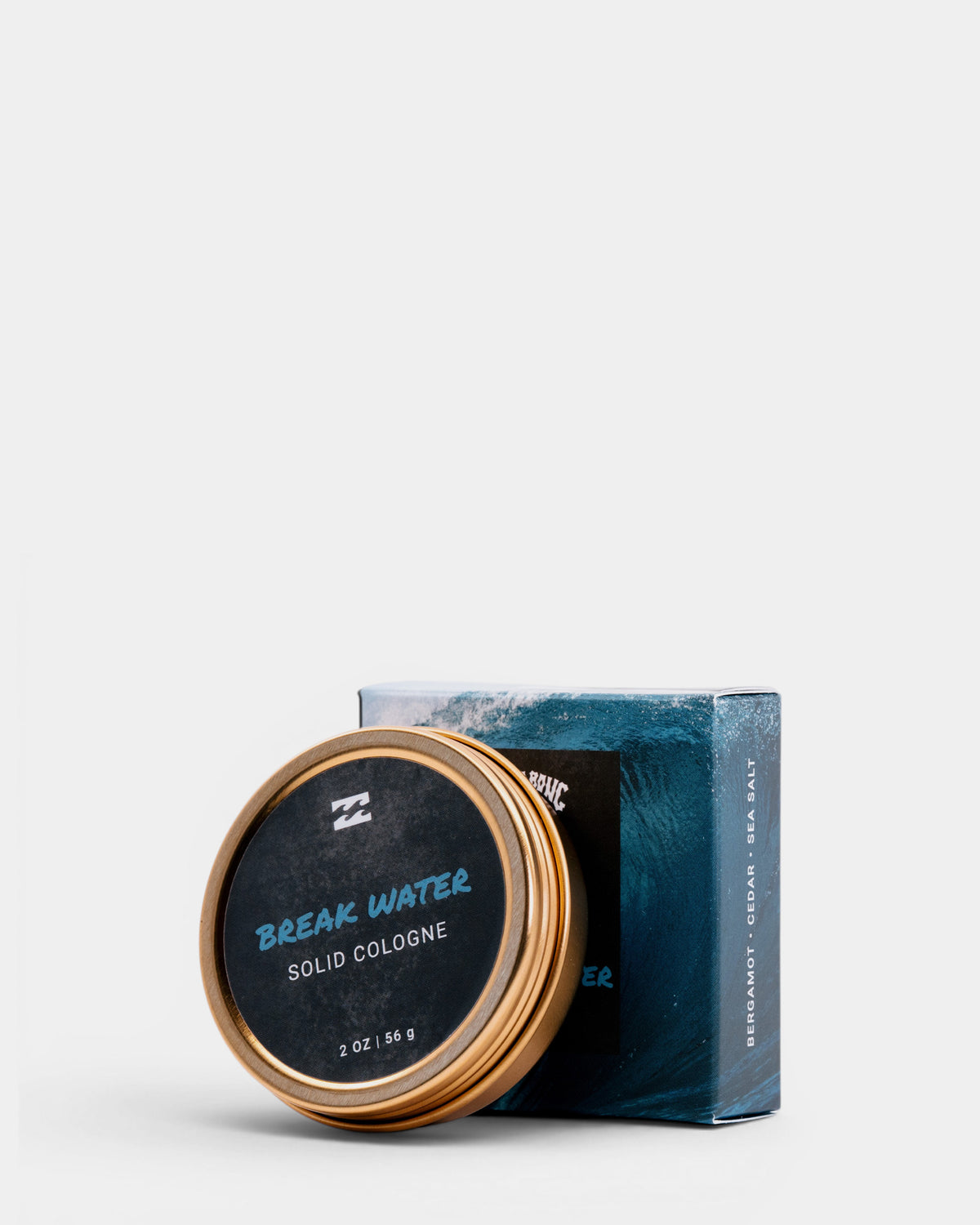 Gold-rimmed tin container with black lid labeled "Break Water Solid Cologne" next to teal and black product box.