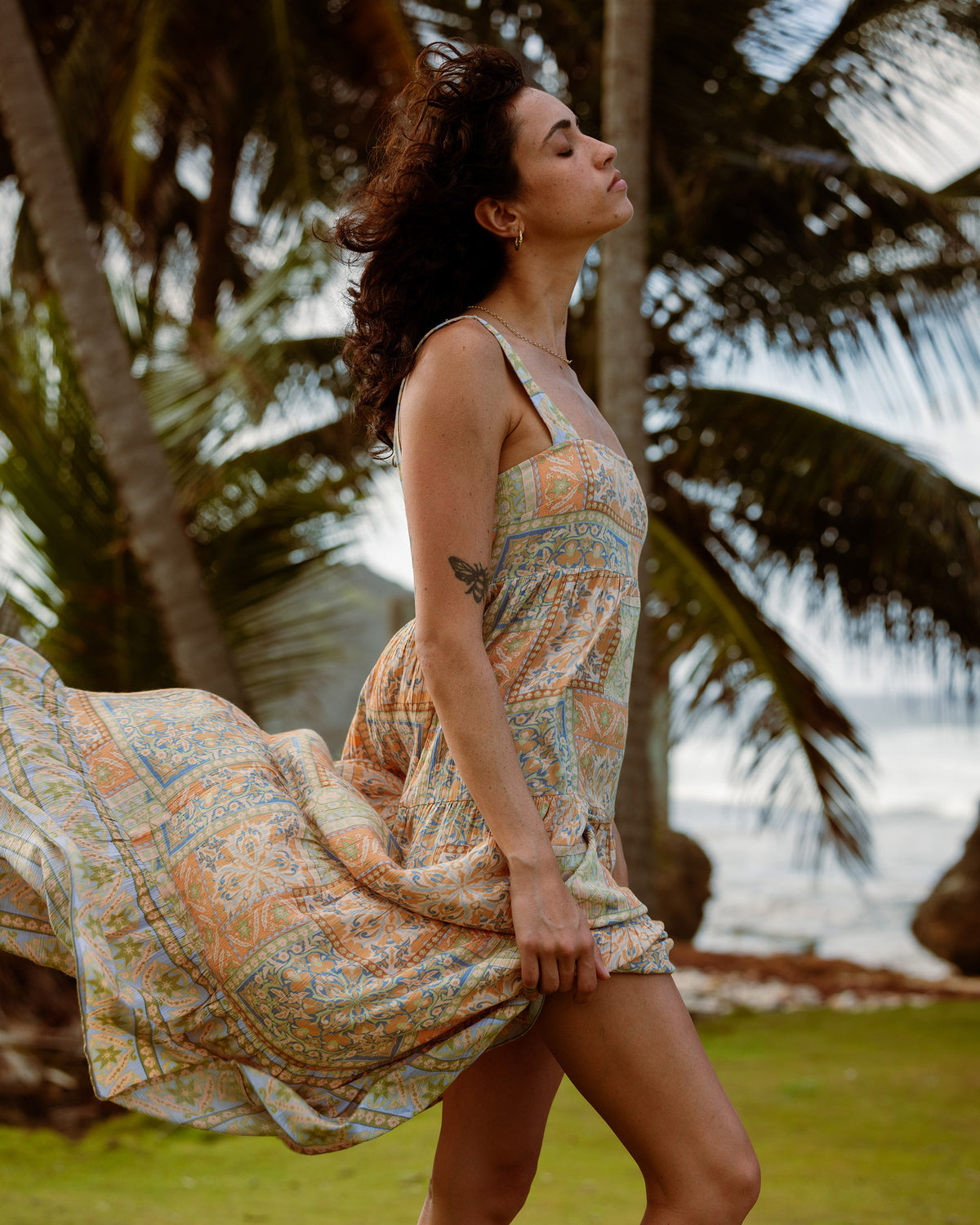 Woman wearing a sleeveless maxi dress with geometric patterned print in blue and orange tones.