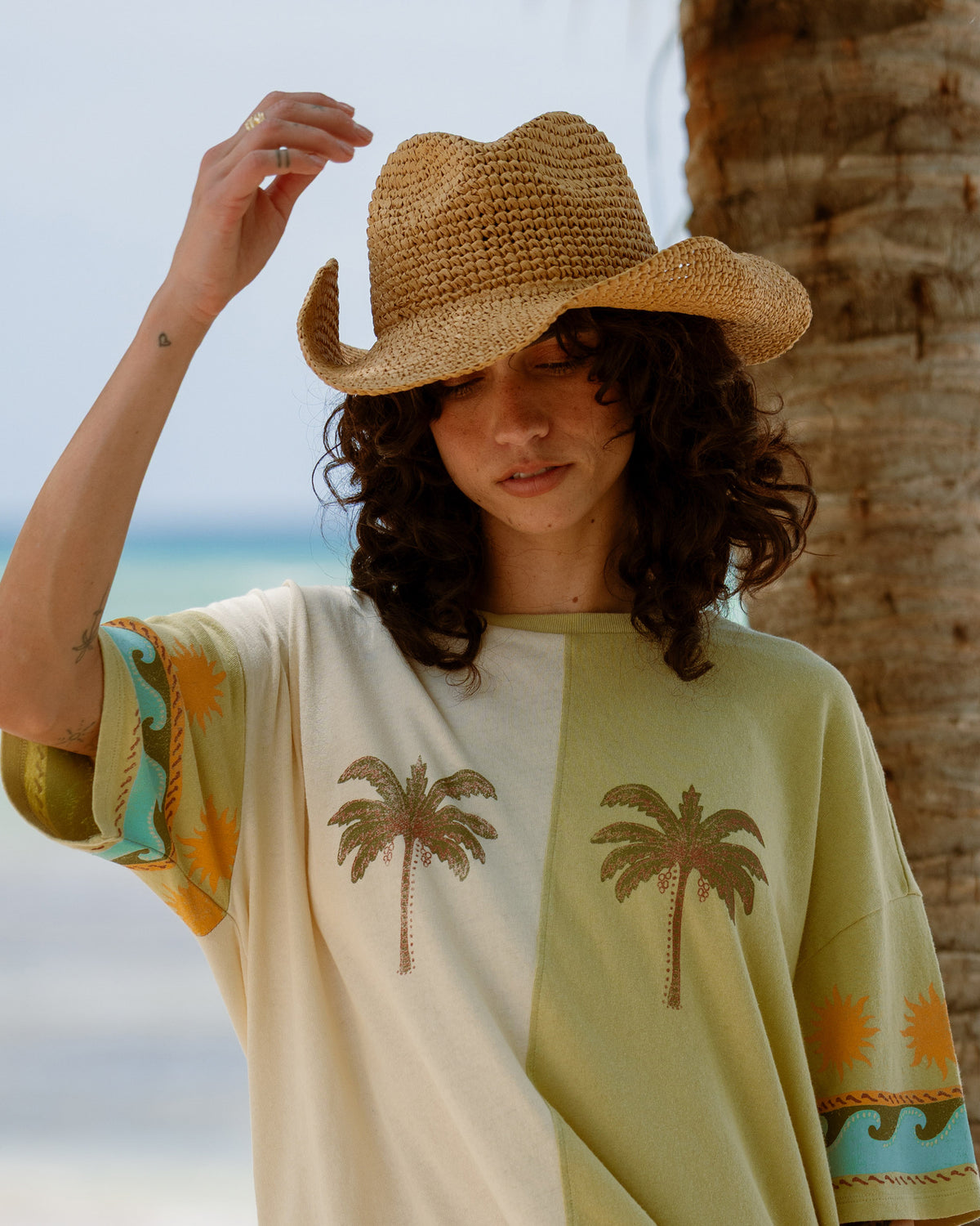 White and sage green short-sleeve t-shirt with split palm tree designs and colorful block panels on sleeves.