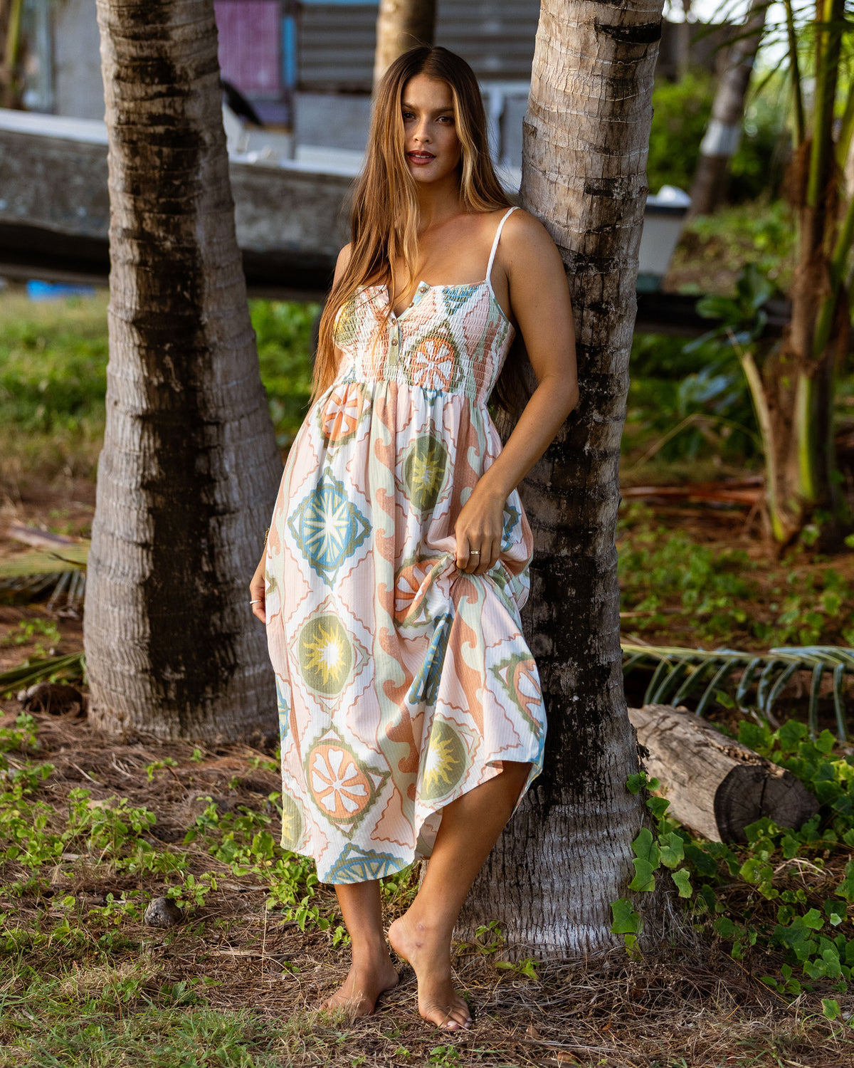 White midi dress with colorful fruit and geometric print, adjustable straps, and gathered bodice.