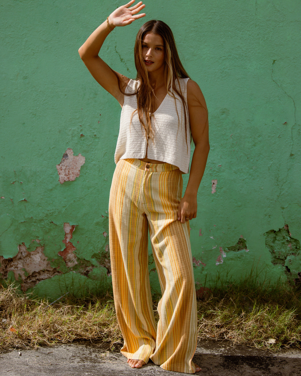 Brown and cream striped elastic waist pants with wide legs worn with a white sleeveless top.