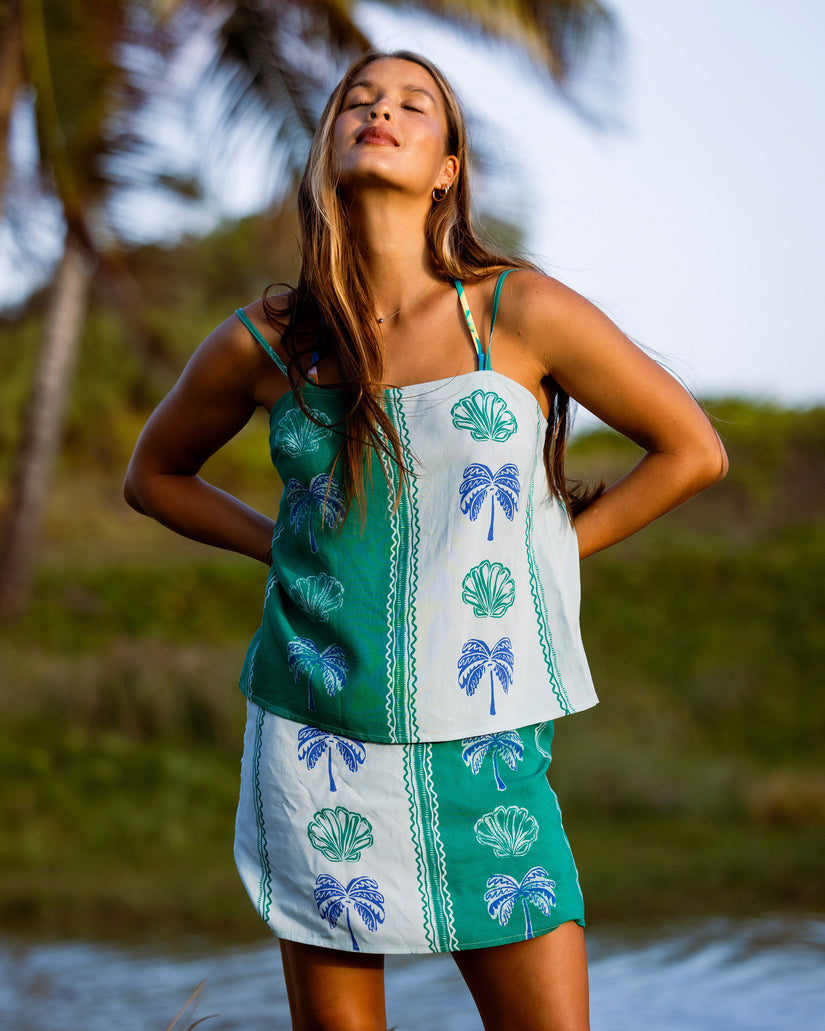 Pool blue and white skirt with printed shell and palm tree motifs and decorative side stripe.