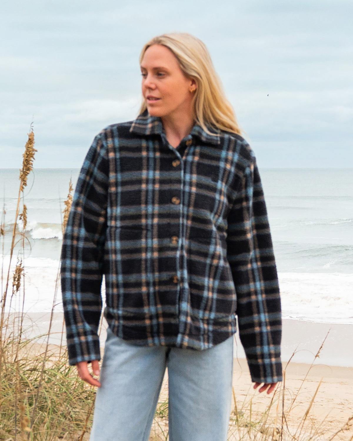 Black and blue plaid sherpa shacket with button front worn over light blue jeans.