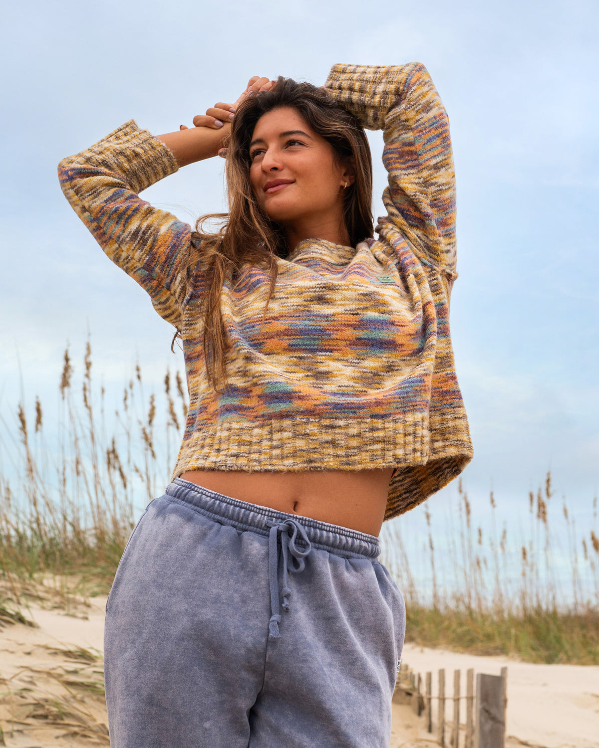 Teak-colored knit sweater with multicolor striped pattern and ribbed texture, worn with blue drawstring pants.