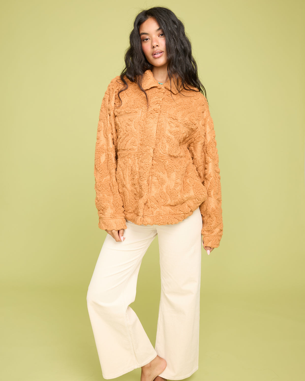 Camel sherpa shacket with textured fabric, button front, and chest pockets worn with cream pants.