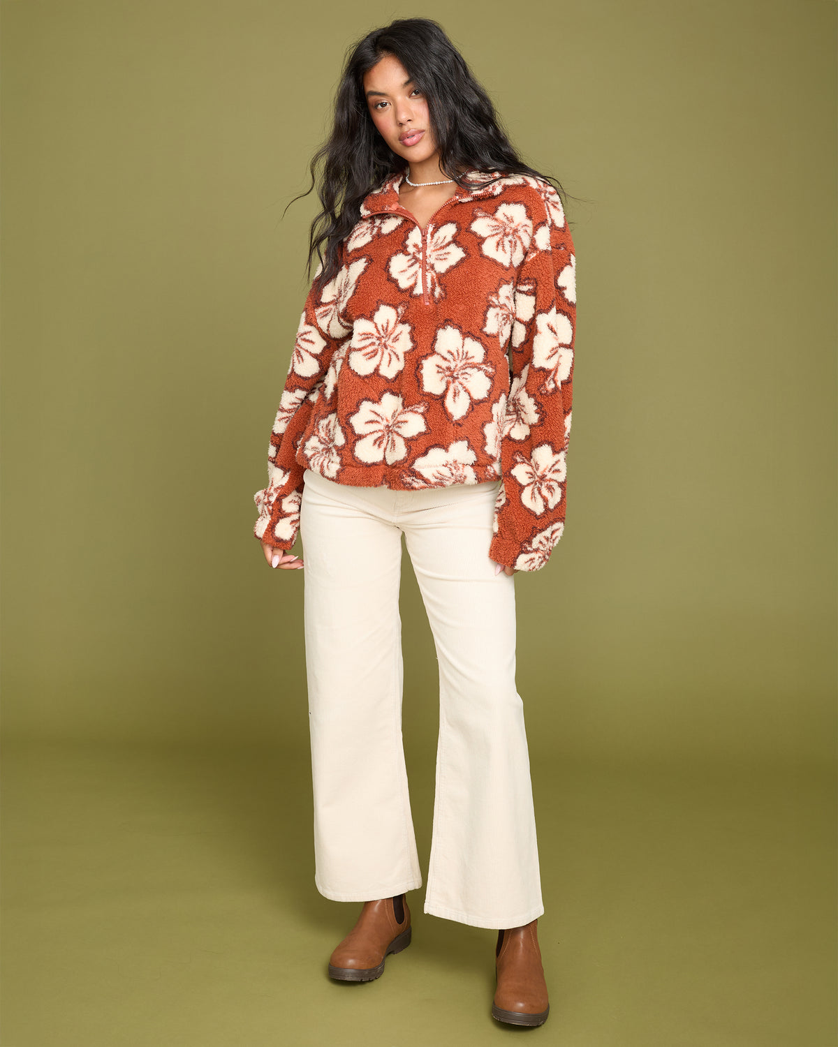 Sedona sherpa half zip sweatshirt with white floral pattern worn with cream pants and brown boots.
