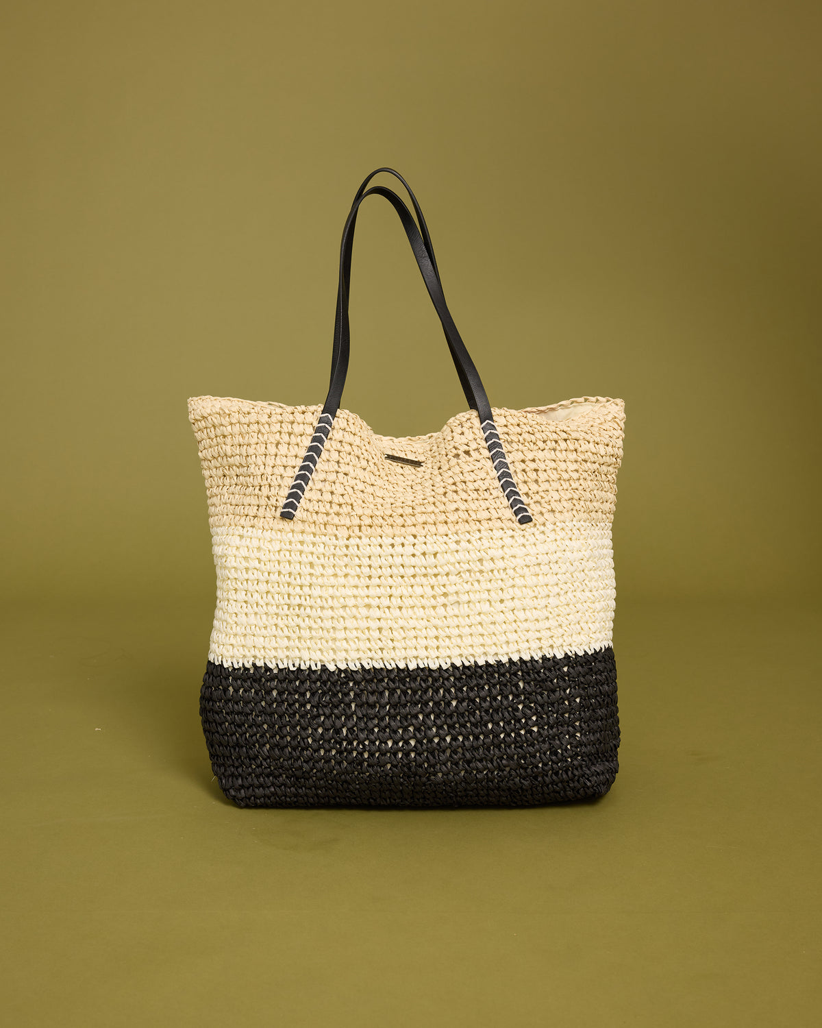 Woven tote bag with natural straw upper half, black woven lower half, and black rope handles.